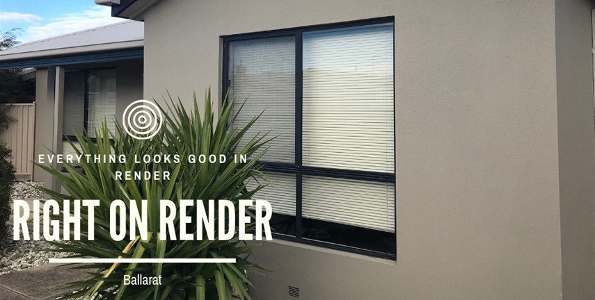 The image showcases the exterior of a building featuring a smooth, beige render finish. It includes a large window with horizontal blinds, framed by a lush green plant, adding a contrast to the neutral tones of the render. The setting appears tidy and well-maintained, with a clear sky in the background.
