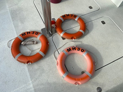 The image features three life buoys positioned on the deck of a boat, with visible markings of 'MH30' on each buoy. The life buoys are essential safety equipment for maritime activities, designed to aid individuals in distress in water. The setting, likely on a vessel used for leisure or rescue purposes, highlights the importance of safety in marine environments. For Imagine Signage, a business providing signwriting services, these life buoys could serve as an example of custom safety signage or branding opportunities. They can create tailored safety signs, labels, or decals to enhance visibility and compliance with safety regulations, particularly in locations frequented by watercraft or councils in the areas they service, such as Manly Vale and Dee Why.