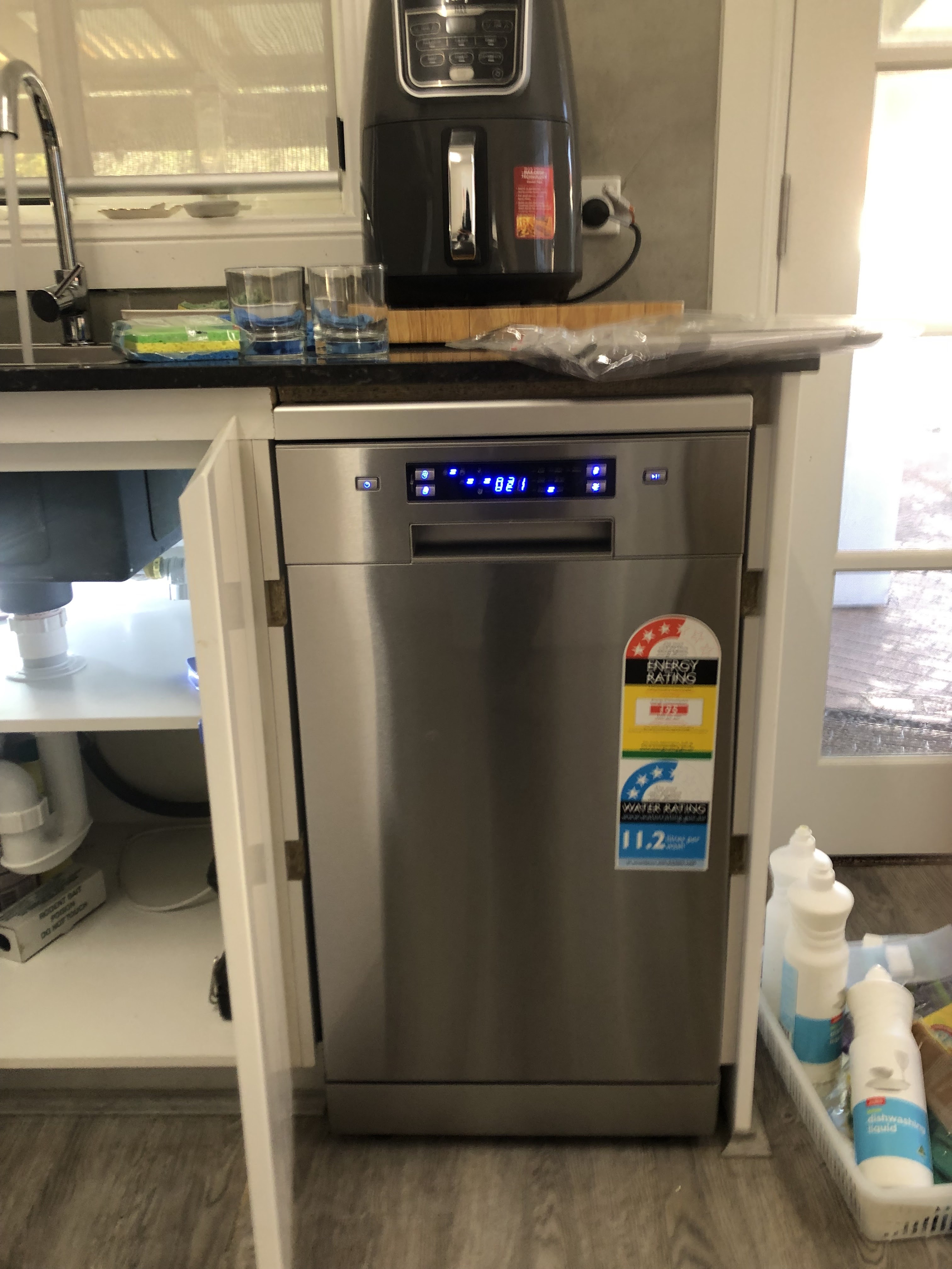 The image displays a neat kitchen space featuring a stainless-steel dishwasher positioned strategically beneath the countertop. To the left, sinks indicate a functional workspace, while the bright ambience suggests a well-lit, modern design. The visible water connection underneath suggests recent plumbing work or installation, highlighting the importance of plumbing services for appliances. This image is relevant to Penrith City Plumbing Services as it illustrates the typical environments in which they operate, emphasising their expertise in appliance connections and plumbing maintenance. The presence of household items near the dishwasher could indicate the residential context in which their services are most often required, making it relatable to local homeowners in Mulgoa and surrounding areas.