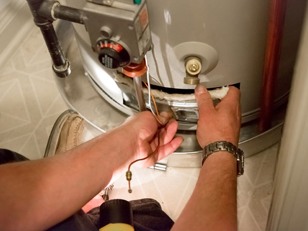 In the image, a plumber is performing maintenance on a hot water heater, which is essential for ensuring that hot water is readily available for residential use. The plumber is using tools to inspect or repair the heating element or connections at the base of the unit. The setting appears to be a typical domestic utility area, suggesting that the business offers services to local homes in Mulgoa and the surrounding areas, including emergency repairs and routine servicing. This proactive maintenance is key to preventing future issues such as leaks or inadequate heating, which can lead to inconvenient service interruptions for customers.