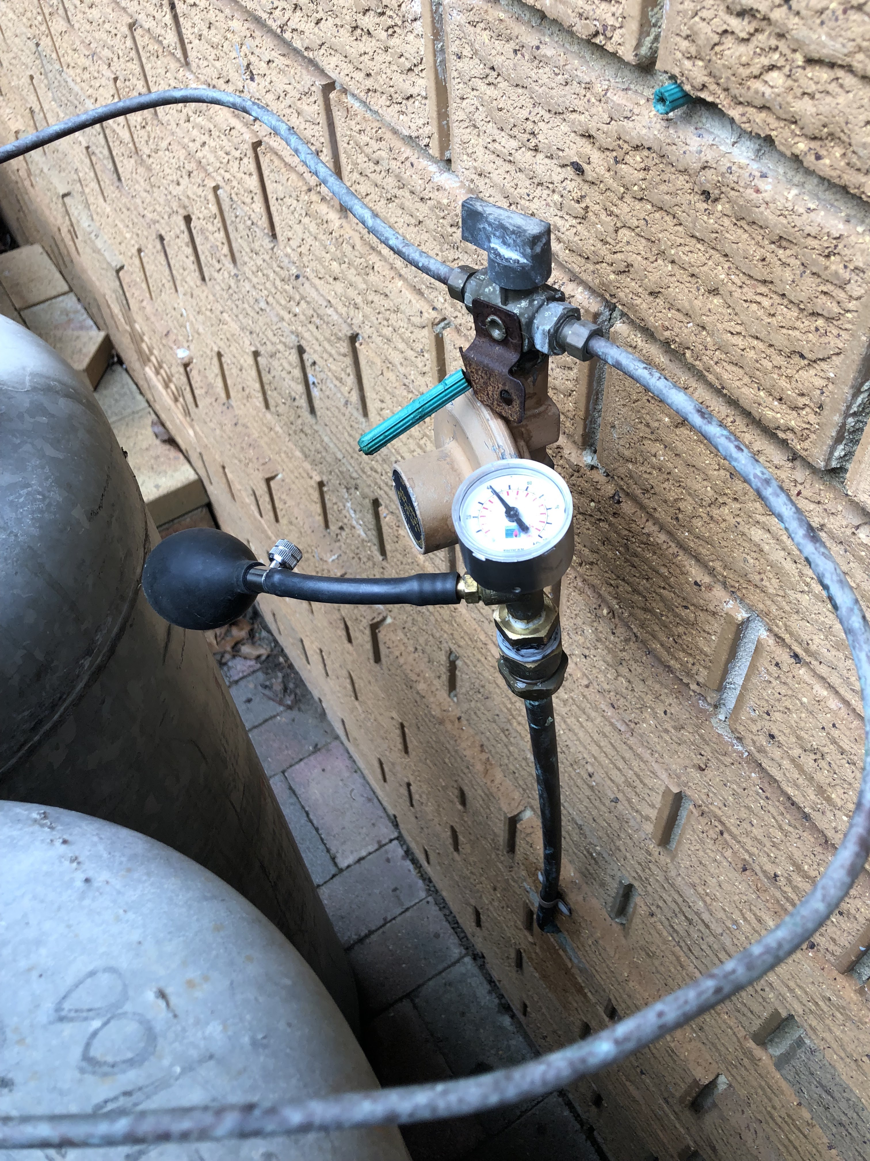 The image depicts a pressure gauge and regulator setup typically used in plumbing systems, possibly connected to gas or water lines. The gauge displays the pressure level, which is crucial for ensuring safe and efficient operation of plumbing installations. The presence of a manually operated pump indicates that this may be a portable or temporary system. This scenario suggests that a plumber from Penrith City Plumbing Services may be checking the pressure levels within a system, potentially as part of routine maintenance or troubleshooting an issue. Ensuring proper pressure is vital to prevent leaks and ensure that water or gas is delivered safely and effectively throughout the property located in Mulgoa or the surrounding serviced areas.