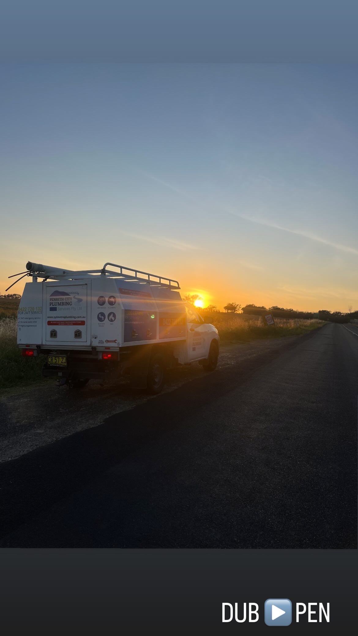 The image depicts a plumbing service vehicle parked on the side of a quiet, rural road during sunset. The van is equipped with a roof rack, likely holding essential plumbing tools and equipment, indicative of the services provided by Penrith City Plumbing Services. The warm hues of the setting sun create a peaceful ambiance, suggesting an evening out in the field, possibly after completing a client job in the surrounding areas of Mulgoa or nearby locations. This scene captures the dedication and commitment to service that the business embodies, as they patrol the local communities of Western Sydney, ready to address any plumbing issues that arise.
