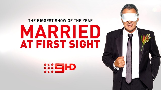 The image features a promotional poster for the reality television show 'Married at First Sight.' It depicts a man in a tuxedo holding flowers, with a blindfold on his eyes, indicative of the show's concept of pairing couples without prior knowledge. The background is bright and minimalistic, primarily showcasing the title and the tagline 'The Biggest Show of the Year.' This format and visual style are designed to attract viewers, highlighting the dramatic and engaging nature of the reality series.