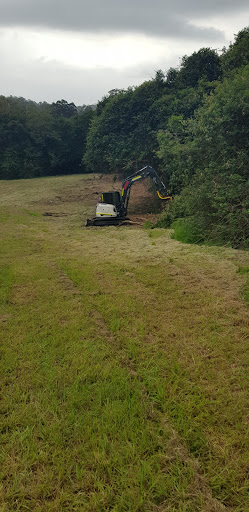 The image depicts a clearing site where a compact excavator is actively engaged in land clearing, surrounded by overgrown vegetation. The ground is mowed and appears freshly cut, suggesting ongoing maintenance or preparation for a larger project. This activity is essential for services offered by Reeper Mulching, particularly in ensuring safe fire trails and open spaces in the Bateau Bay area and nearby locations. The equipment, equipped for mulching, underscores the focus on efficient removal of shrubs and trees, promoting better accessibility and fire safety in natural spaces.