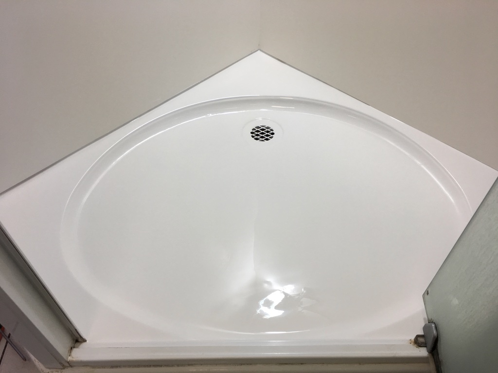The image features a clean and well-maintained corner shower base exhibiting a smooth, glossy white finish. This space appears to be prepared for either installation or resurfacing, showcasing the pristine condition that client renovations can achieve. The lack of water stains or grime suggests that this area has been recently cared for, highlighting the attention to detail that Coastline Bath Resurfacing aims to provide in their services. With the smooth curves of the shower base designed to fit snugly into the corner, it maximises space efficiency. This type of fixture aligns with modern bathroom aesthetics, ideal for Coastline's renovation projects across Kyogle and surrounding areas. It symbolizes the quality workmanship and results clients can expect when opting for professional resurfacing services.