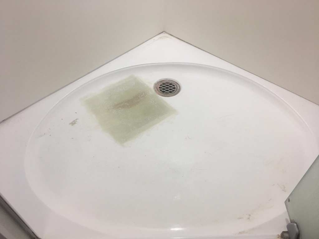 The image depicts a round shower base that appears to be in need of significant cleaning and resurfacing. The surface displays a noticeable patch of discolouration, likely indicating mould or mildew buildup around the drain area, which is a common issue in bathrooms. The edges of the shower base are somewhat worn, and overall, the area gives the impression of being neglected and in poor condition. This situation highlights the importance of professional bathroom renovation services in revitalising such spaces. Coastline Bath Resurfacing can effectively address these issues by restoring the shower base to a pristine condition, offering both aesthetic improvement and enhancing the hygiene of the bathroom.