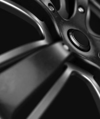 The image showcases a close-up view of a black alloy wheel, highlighting its intricate design and finish. This aesthetic can be appealing to prospective customers who appreciate automotive aesthetics and may relate to the services offered by a mechanic. The positioning and angle of the shot emphasise the wheel's details, drawing attention to its quality and craftsmanship, which aligns with the mechanical services of True Blue Mechanical that focus on enhancing vehicle performance and appearance.