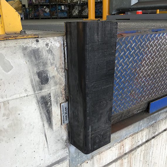 The image depicts a vertically positioned steel block, likely a protective bumper or guide, mounted on a concrete wall. This installation is commonly found at loading docks or industrial facilities, serving to protect the wall and surface from damage caused by incoming vehicles or equipment during loading and unloading operations. The steel block's robust composition indicates high durability, essential for frequent impacts, making it a vital element in steel fabrication and structural safety. The background suggests an industrial environment, typical for companies like Rosa Engineering PTY Ltd., which specializes in steel fabrication. Such installations reflect the commitment to quality and safety in their projects.