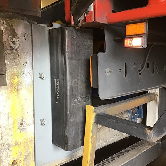 The image showcases a close-up view of a robust steel structure, likely part of a larger steel fabrication project. The focus appears to be on a black rubber block or bumper secured to the steel frame—likely intended for impact protection or cushioning against equipment or machinery. This detail highlights the precision engineering and attention to safety features in the fabrication process. The surroundings include metal beams and safety lighting, indicative of a busy fabrication or loading area where steel components are assembled. This is a crucial setting for Rosa Engineering PTY Ltd., as it reflects their commitment to high-quality steel fabrication services in Penrith and surrounding areas.