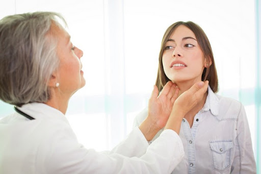 A healthcare professional, likely a doctor, is examining a young woman's throat in a well-lit medical setting. This interaction suggests a thorough health checkup, reflecting the attentive and personalised care provided at the Medical Centre in Maroubra and its surrounding suburbs.